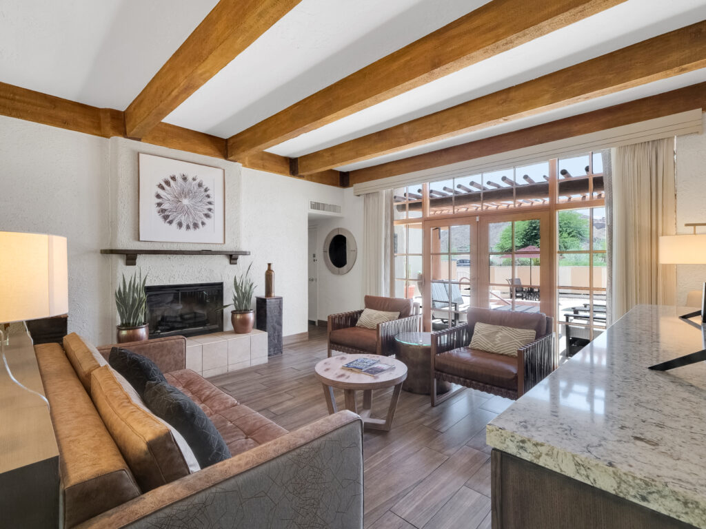 Spacious living room in Camelback Inn Unit 569 with wood beam ceiling, fireplace, seating area, and patio doors leading to private outdoor space