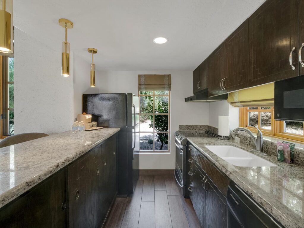 Full galley kitchen in Camelback Inn Unit 569 with granite countertops, stove, oven, microwave, refrigerator, and sink