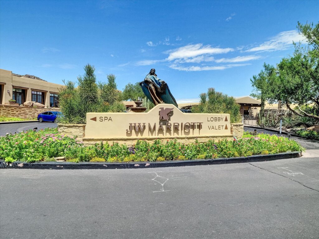 Entrance sign at JW Marriott Scottsdale Camelback Inn Resort & Spa with landscaped grounds and statue, representing a luxury condo-hotel investment property in Scottsdale Arizona.