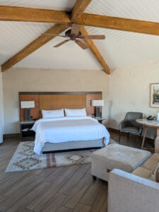 The primary living space of Unit 144 features vaulted wood-beamed ceilings, a king bed, comfortable seating area, and updated finishes that create the feel of a private luxury casita. Located within the JW Marriott Camelback Inn Resort in Scottsdale, Arizona.